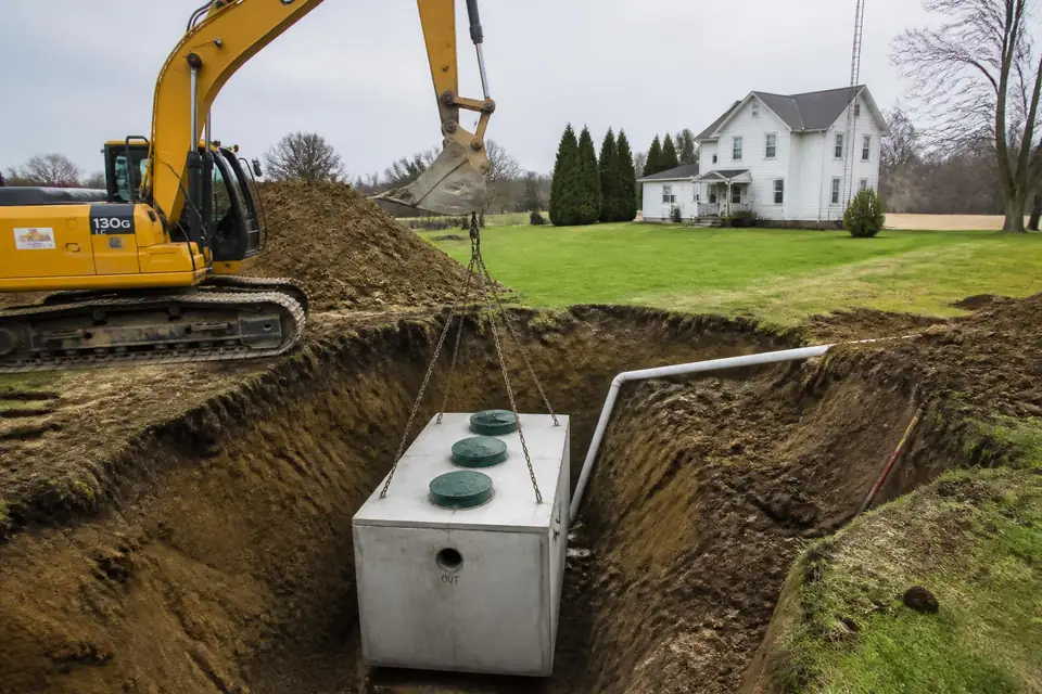 New concrete septic tank being lowered into an excavated trench at a rural Ohio residence